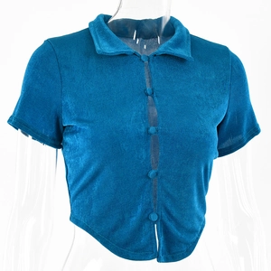 Detail of blue cropped cardigan with fabric-covered buttons and irregular pointed hemline