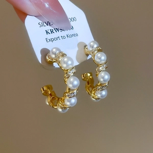 Detailed macro view of 925 silver gold-plated C-shaped earrings with pearls and zircons