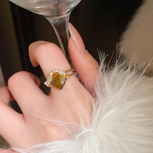 Detail of snake ring featuring brown gemstone with pearl and zircon accents on golden band