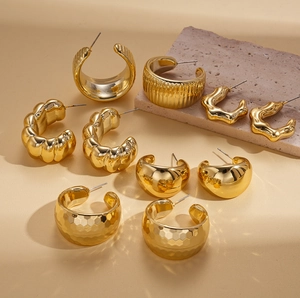 Detailed view of ten pairs of golden geometric flower stud earrings with a shiny finish