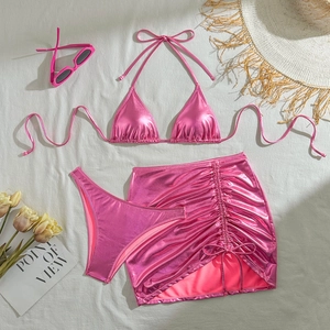 Detailed flat lay of pink metallic three-piece bikini set with drawstring skirt and sunglasses