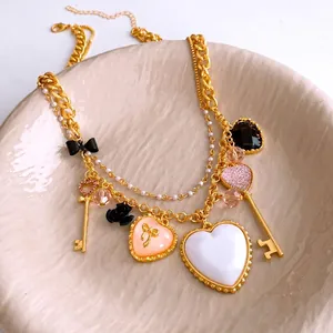 Collana vintage dorata a strati con ciondoli a cuore e chiave, perle e fiocchi