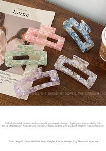 Detail of large acetate hair claws with marble texture and delicate pearl accents