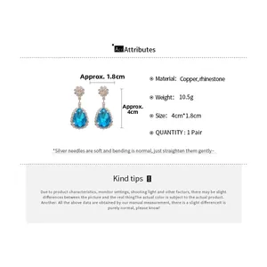 Detailed view of teardrop earrings with blue crystals and silver needles on white background