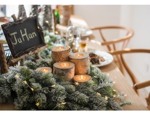 Detail of natural birch wood candle holders with tea lights and festive pine decorations
