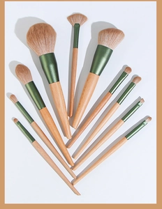 Flat lay of 10-piece wooden handle makeup brush set with green metal ferrules
