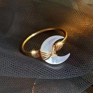 Detailed close-up of handmade gold wire-wrapped ring with crescent moon mother of pearl