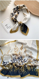Detail of vintage plant print silk square scarf in ginger and black on a wooden tray