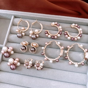 Detailed display of pearl hoop earrings with zircon accents on a gray velvet jewelry tray