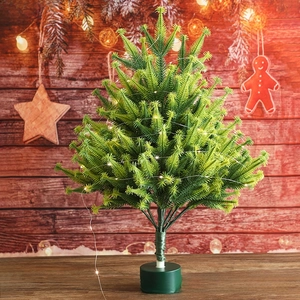 Miniature flocked Christmas tree with warm LED lights on a rustic wooden background