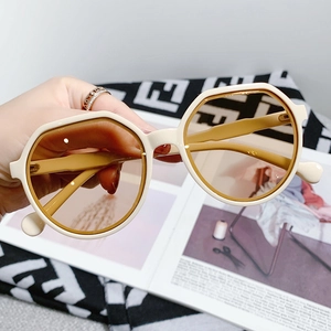 Detailed close-up of cream resin sunglasses with light tea polygonal transparent lenses