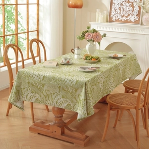 Detail of green cotton linen tablecloth with white floral pattern on a wood table