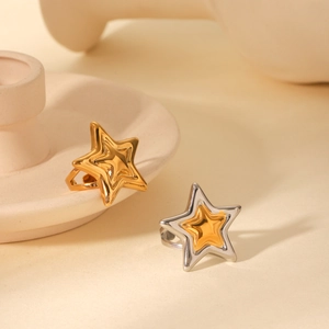 Detailed view of two-tone gold and silver star-shaped rings on beige ceramic display