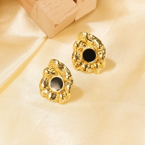 Dettaglio macro di orecchini placcati oro 18k con inserto nero su tessuto di seta