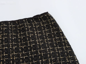 Dettaglio della vita di una gonna in tweed con trama in filato nero e oro e texture
