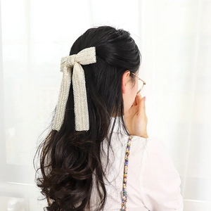 Elegant beige bow hair clip with pearl beads on wavy dark hair, handmade hair accessory