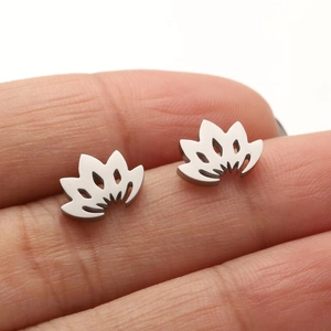 Macro shot of miniature lotus earrings on fingertip showing precise laser cut metal detail