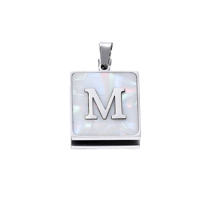 Macro detail of silver square pendant with white shell inlay and letter M engraving