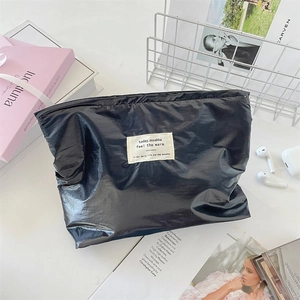Detail of black glossy makeup bag with crinkled texture and stylish fabric label