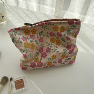 Vue détaillée d'une trousse à maquillage en toile aux motifs floraux sur fond beige