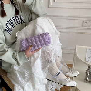 Detail of light purple bubble textured pouch held against a green New York sweatshirt