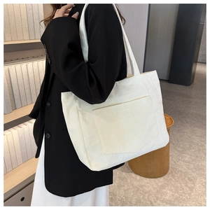 Close-up of beige corduroy tote bag featuring a front pocket with XINRUI GOOD text