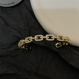 Elegant gold-tone link bracelet with shimmering crystals in a minimalist jewelry display