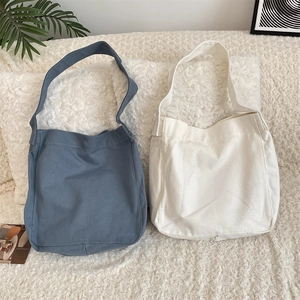 Borse tote in tela grigio-blu e beige con spalline larghe su superficie pelosa