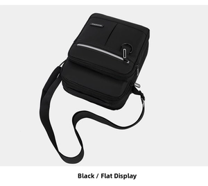 Flat lay view of a black oxford fabric crossbody bag with reflective strip and front zipper