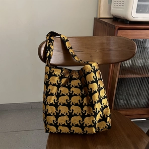 Gros plan détaillé de la broderie jacquard d'éléphant doré sur sac bandoulière noir