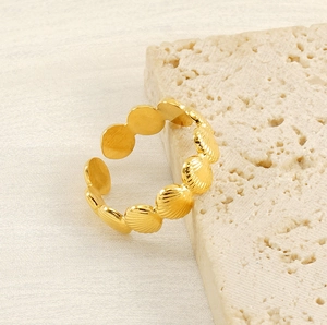 Detailed close-up of golden shell design open ring on natural stone background