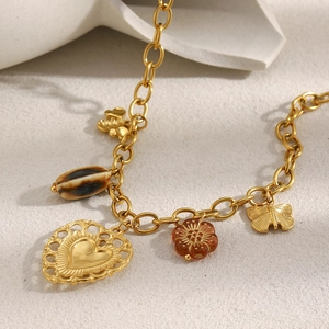 Macro shot of gold-plated O-chain necklace with heart, butterfly and shell pendants