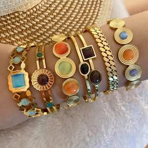 Bohemian style stackable gold bangles with colorful gemstones on a resort background
