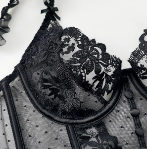 Detail of black lace corset featuring sheer polka dot mesh and embroidered floral patterns