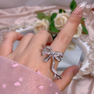 Elegant silver bow knot ring with cubic zirconia stones on silk fabric with flowers