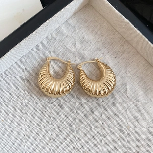 Macro view of gold hoop earrings with croissant-style textures and polished finish