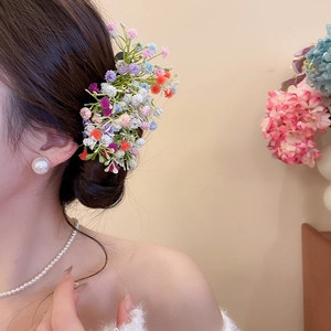 Detail of colorful acrylic flower cluster hair clip styled on a side bun with pearls