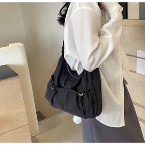 Detail shot of black nylon hobo bag with drawstring pleats and silver zipper accents