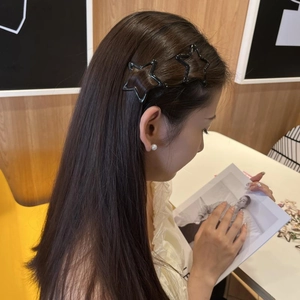 Detailed view of model wearing black star-shaped hair clips and pearl earrings in a cafe