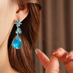 Détail de boucles d'oreilles élégantes avec goutte bleue et zircons floraux pour femme