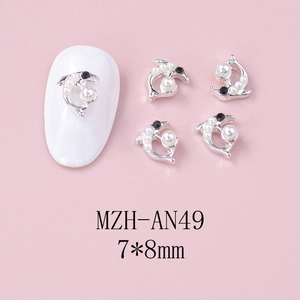 Macro detail of 7x8mm silver dolphin nail charms with pearls on pink textured background