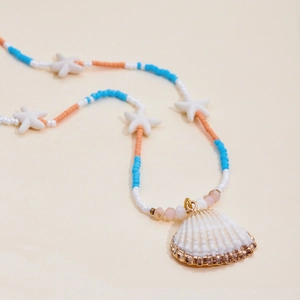 Detail of seashell necklace with gold trim, blue and orange beads on a beige background