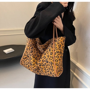 Detail of a large leopard print tote bag with brown straps and canvas texture design