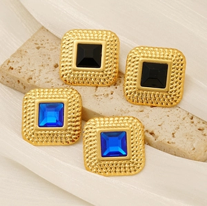 Macro view of vintage square zircon earrings on stone and silk background