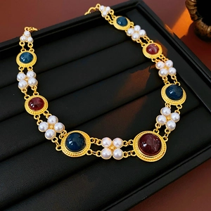Detail of vintage necklace with blue and red gemstones and white pearl flower links