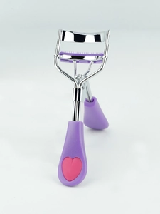 Detail of eyelash curler with purple comb and heart handle on white background