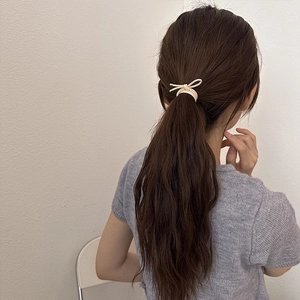 Détail d'un chouchou élastique beige minimaliste avec boucle en métal sur une queue de cheval