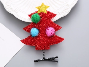 Detalle de una pinza para el pelo de árbol de Navidad con lentejuelas rojas y pompones