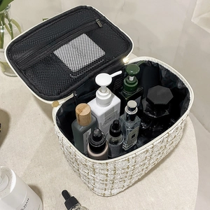 White tweed makeup bag with gold hardware and interior mesh pocket for storage