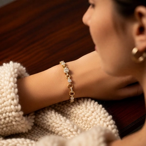 Close-up of gold chain bracelet with zircon geometric clusters on a knitted sleeve